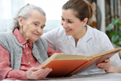 senior woman together with a nurse watching a photo album